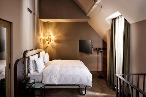 a bedroom with a bed with white sheets and a tv at Telegraphenamt in Berlin
