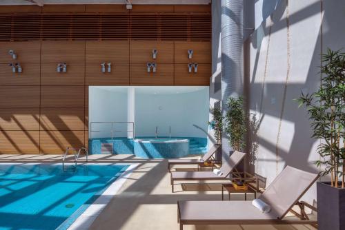 uma vista para uma piscina com cadeiras e uma piscina em Hilton Geneva Hotel and Conference Centre em Genebra