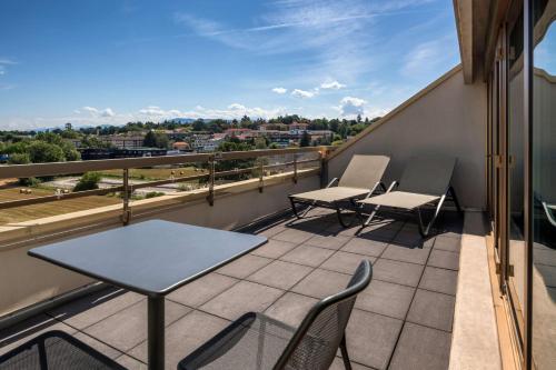 a balcony with chairs and a table on a building at Hilton Geneva Hotel and Conference Centre in Geneva