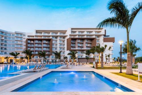 Embassy Suites By Hilton Aruba Resort في شاطئ بالم إيغل: فندق فيه مسبح امام مبنى