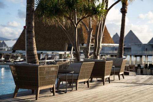 a group of chairs and tables next to a pool at DoubleTree by Hilton Noumea Ilot Maitre Resort in Ilot Maitre