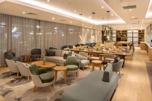 a restaurant with couches and tables and chairs at Hilton Garden Inn Umhlanga Arch in Durban