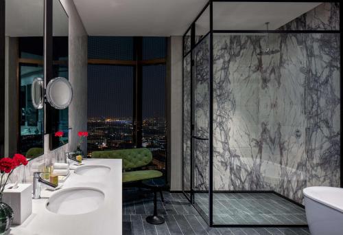 DoubleTree by Hilton Dubai M Square Hotel & Residences في دبي: حمام مع مغسلتين ودش