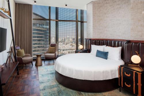 DoubleTree by Hilton Dubai M Square Hotel & Residences في دبي: غرفة نوم بسرير كبير ونافذة كبيرة