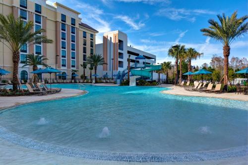 una piscina en el complejo con palmeras y hoteles en Home2 Suites By Hilton Orlando Flamingo Crossings, FL en Orlando