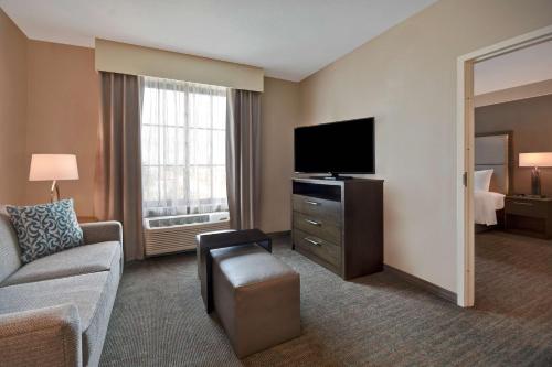 a living room with a couch and a television in a hotel room at Homewood Suites By Hilton Orlando Flamingo Crossings, Fl in Orlando