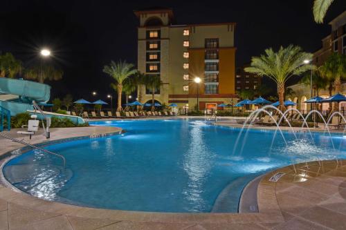 a large swimming pool with a water fountain at night at Home2 Suites By Hilton Orlando Flamingo Crossings, FL in Orlando