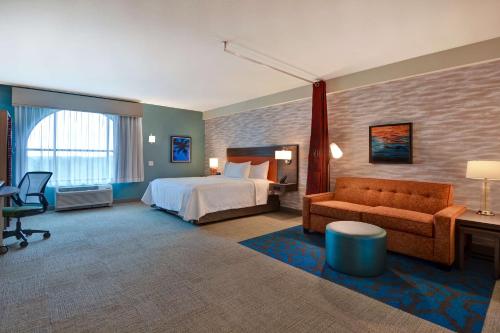 Home2 Suites By Hilton Orlando Flamingo Crossings, FL في أورلاندو: غرفه فندقيه بسرير واريكه