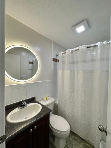 een badkamer met een toilet, een wastafel en een spiegel bij August Jack Motor Inn in Squamish