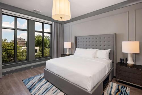 - une chambre avec un grand lit blanc et des fenêtres dans l'établissement Hilton Club Liberty Place Charleston, à Charleston