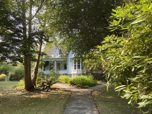 a white house with a tree and a sidewalk at Shaw House Inn in Ferndale