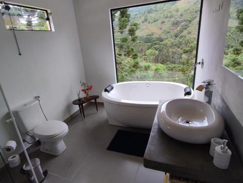 a bathroom with a tub and a toilet and a sink at Angatu chalé in Gonçalves