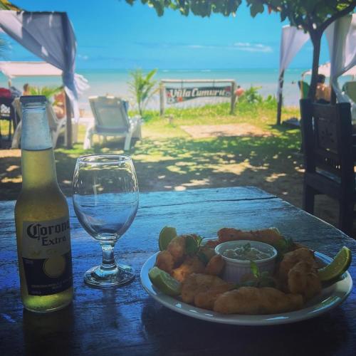 una mesa con un plato de comida y una copa de vino en Pousada Villa Cumuru, en Cumuruxatiba