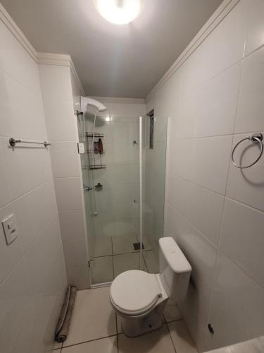 uma casa de banho branca com um chuveiro e um WC. em Apartamento centro Efapi ideal para trabalho ou estudo em Chapecó