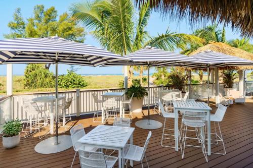 a deck with tables and chairs and umbrellas at Hilton Garden Inn St. Pete Beach, FL in St. Pete Beach