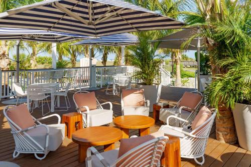 a deck with chairs and tables and umbrellas at Hilton Garden Inn St. Pete Beach, FL in St Pete Beach