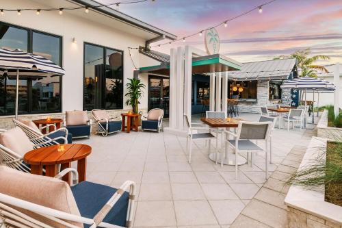 a patio with chairs and tables and umbrellas at Hilton Garden Inn St. Pete Beach, FL in St Pete Beach
