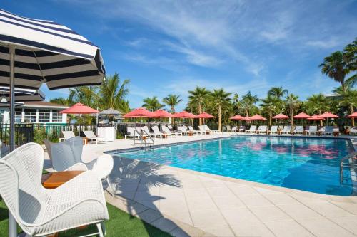 uma piscina com cadeiras e guarda-sóis em Hilton Garden Inn St. Pete Beach, FL em St. Pete Beach