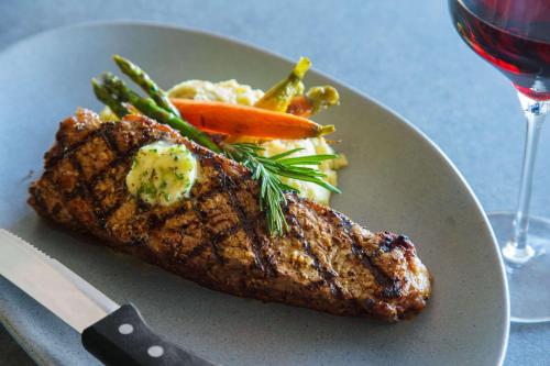 a plate of food with meat and vegetables and a glass of wine at Hilton Garden Inn St. Pete Beach, FL in St Pete Beach