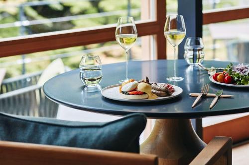 Una mesa con un plato de comida y copas de vino. en ROKU KYOTO, LXR Hotels & Resorts by Hilton, en Kioto