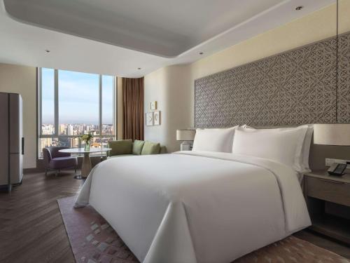 a large white bed in a hotel room with a view at Conrad Urumqi in Ürümqi