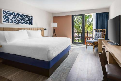 um quarto de hotel com uma cama, uma secretária e uma televisão em Hilton Garden Inn St. Pete Beach, FL em St. Pete Beach
