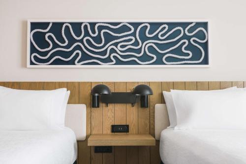 a hotel room with two beds and a painting on the wall at Hilton Garden Inn St. Pete Beach, FL in St Pete Beach