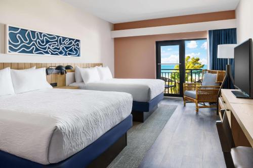 a hotel room with two beds and a television at Hilton Garden Inn St. Pete Beach, FL in St Pete Beach