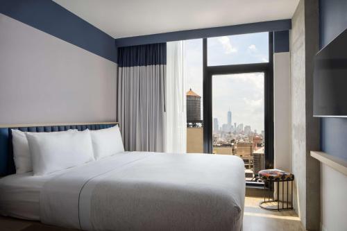 a bedroom with a large bed and a large window at Motto by Hilton New York City Chelsea in New York