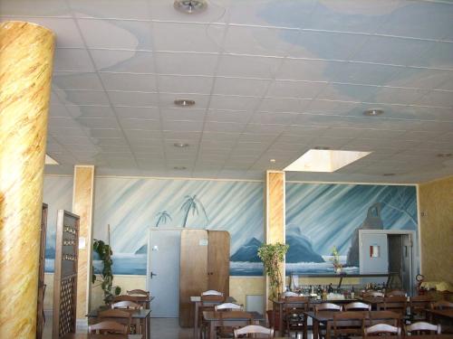 a dining room with tables and chairs and a painting on the wall at Il Bivio Hotel in Carmagnola