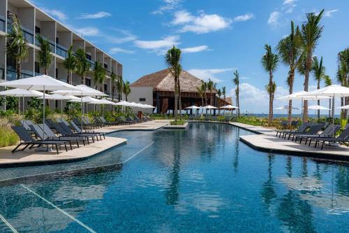 una piscina en el complejo con sillas y sombrillas en Hilton Tulum Riviera Maya All-Inclusive Resort en Tulum