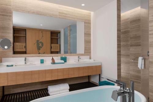 een badkamer met 2 wastafels, een bad en een spiegel bij Hilton Tulum Riviera Maya All-Inclusive Resort in Tulum