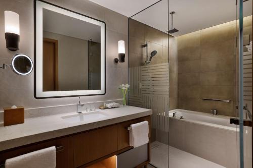 DoubleTree by Hilton Sharjah Waterfront Hotel And Residences في الشارقة: حمام مع حوض وحوض ومرآة