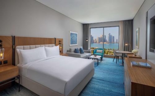 a bedroom with a large white bed and a living room at DoubleTree by Hilton Sharjah Waterfront Hotel And Residences in Sharjah