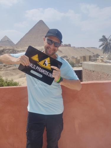 a man holding a sign with the pyramids in the background at El Khalil Pyramids View Inn in Cairo