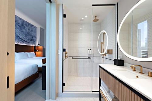 a bathroom with a bed and a shower and a sink at Tempo By Hilton New York Times Square in New York
