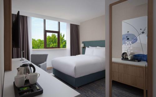 a hotel room with a bed and a desk and a mirror at DoubleTree by Hilton Shymkent in Shymkent