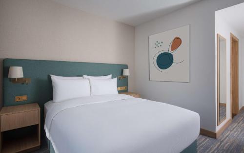a bedroom with a white bed and a green headboard at DoubleTree by Hilton Shymkent in Shymkent