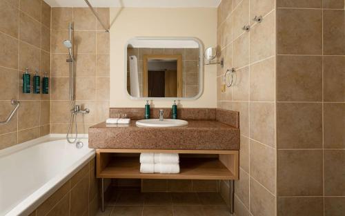 a bathroom with a sink and a tub and a mirror at DoubleTree by Hilton Shymkent in Shymkent