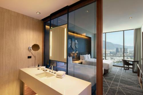 a bathroom with a sink and a room with a bed at Hilton Monterrey Valle in Monterrey