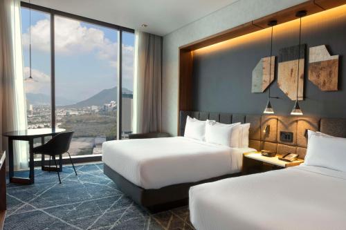 a hotel room with two beds and a desk at Hilton Monterrey Valle in Monterrey