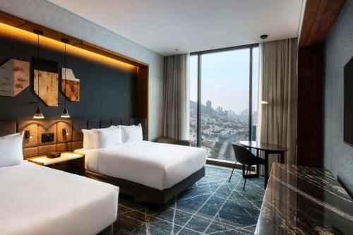 a hotel room with two beds and a desk at Hilton Monterrey Valle in Monterrey