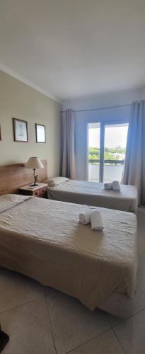 ヴィラモウラにあるGolf & Mar - T2 Apartmentのベッド2台と窓が備わるホテルルームです。