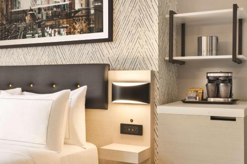 a bedroom with a bed and a nightstand with a clock at DoubleTree by Hilton New York Midtown Fifth Ave in New York