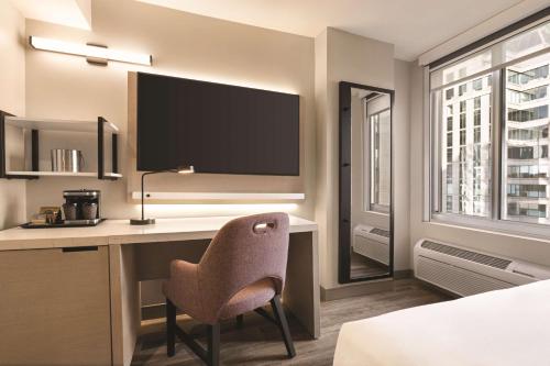 a hotel room with a desk with a chair and a tv at DoubleTree by Hilton New York Midtown Fifth Ave in New York