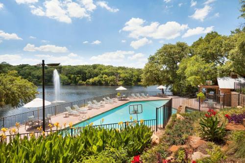 a swimming pool next to a lake with a fountain at Hilton DFW Lakes Executive Conference Center in Grapevine