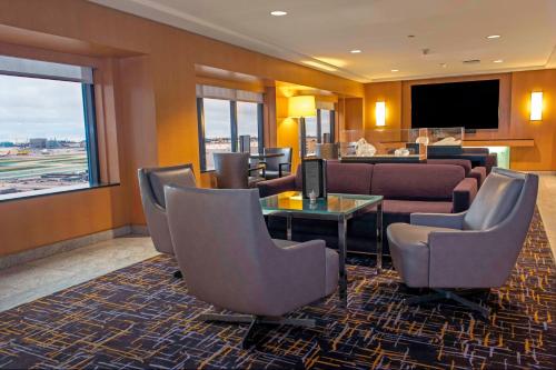 a hotel room with a waiting area with chairs and a television at Hilton Los Angeles Airport in Los Angeles