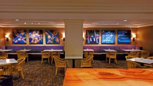 a restaurant with tables and chairs and paintings on the walls at Hilton Los Angeles Airport in Los Angeles