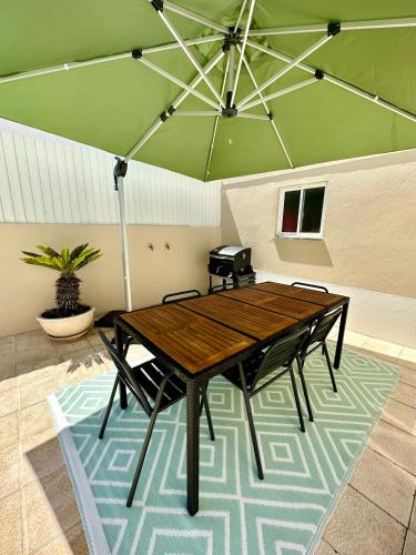 a wooden table and chairs with a green umbrella at A Villa Fortuna in Santo André