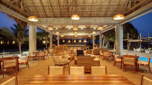 a restaurant with tables and chairs on a deck at Indura Beach & Golf Resort Curio Collection By Hilton in Tela